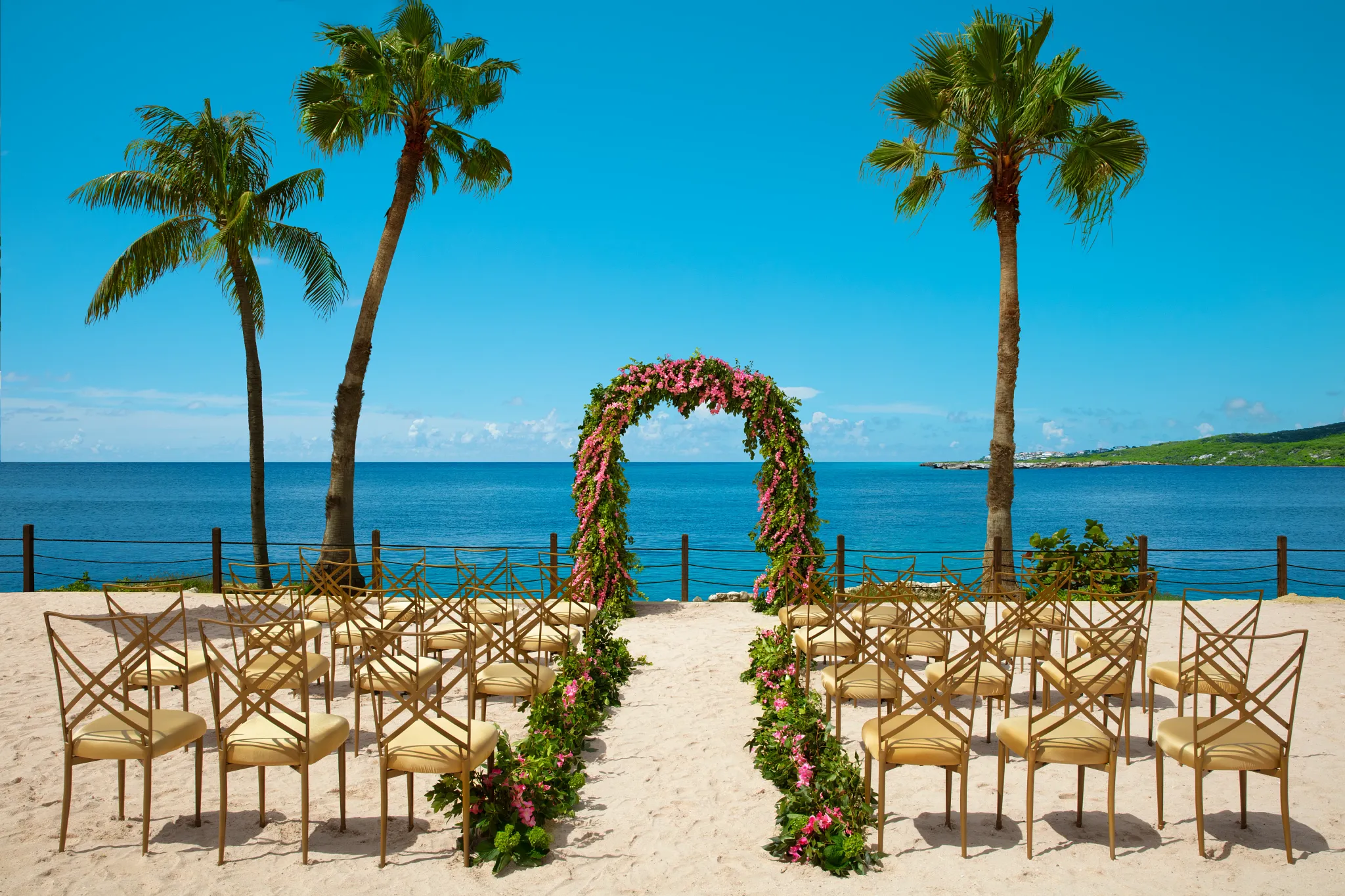 Elegant beach wedding setup with floral arch overlooking the ocean at Dreams Curaçao Resort.