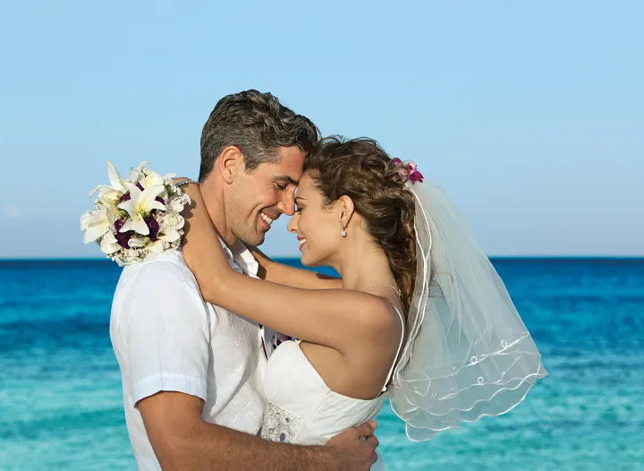 Bride and groom embracing on the beach with turquoise ocean at Dreams Curaçao Resort
