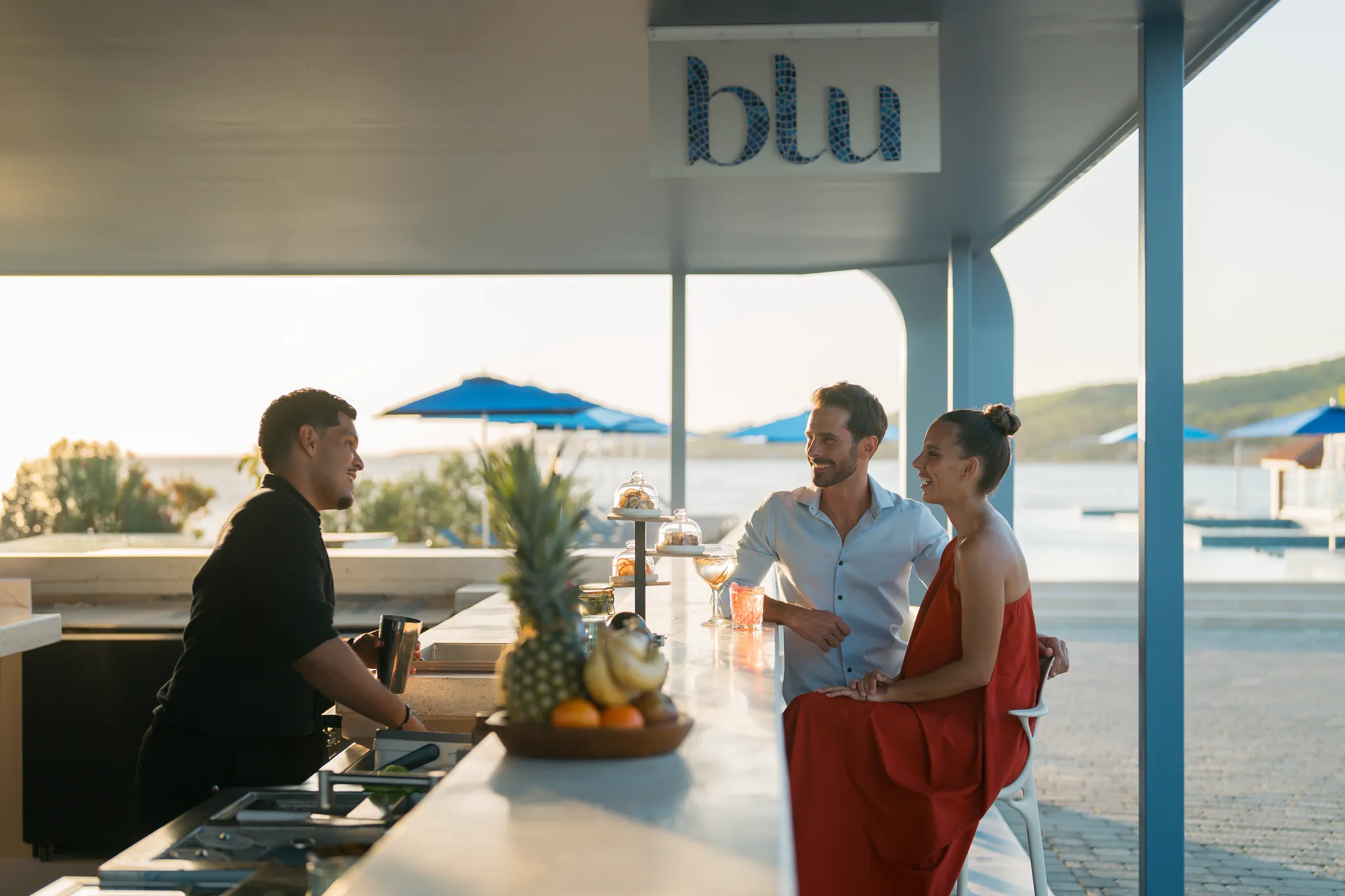 Couple enjoying cocktails at Blu Bar with ocean views at Dreams Curaçao Resort.