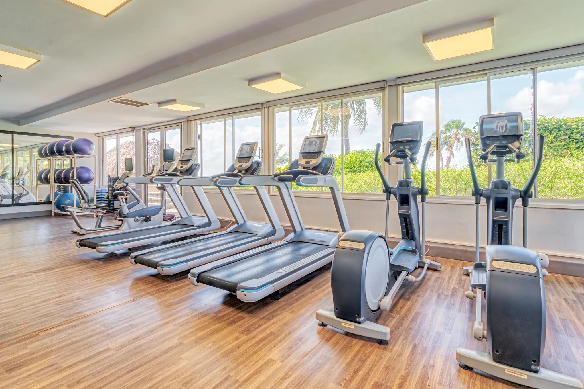 Cardio machines with tropical outdoor views inside the fitness center at Dreams Curaçao Resort.