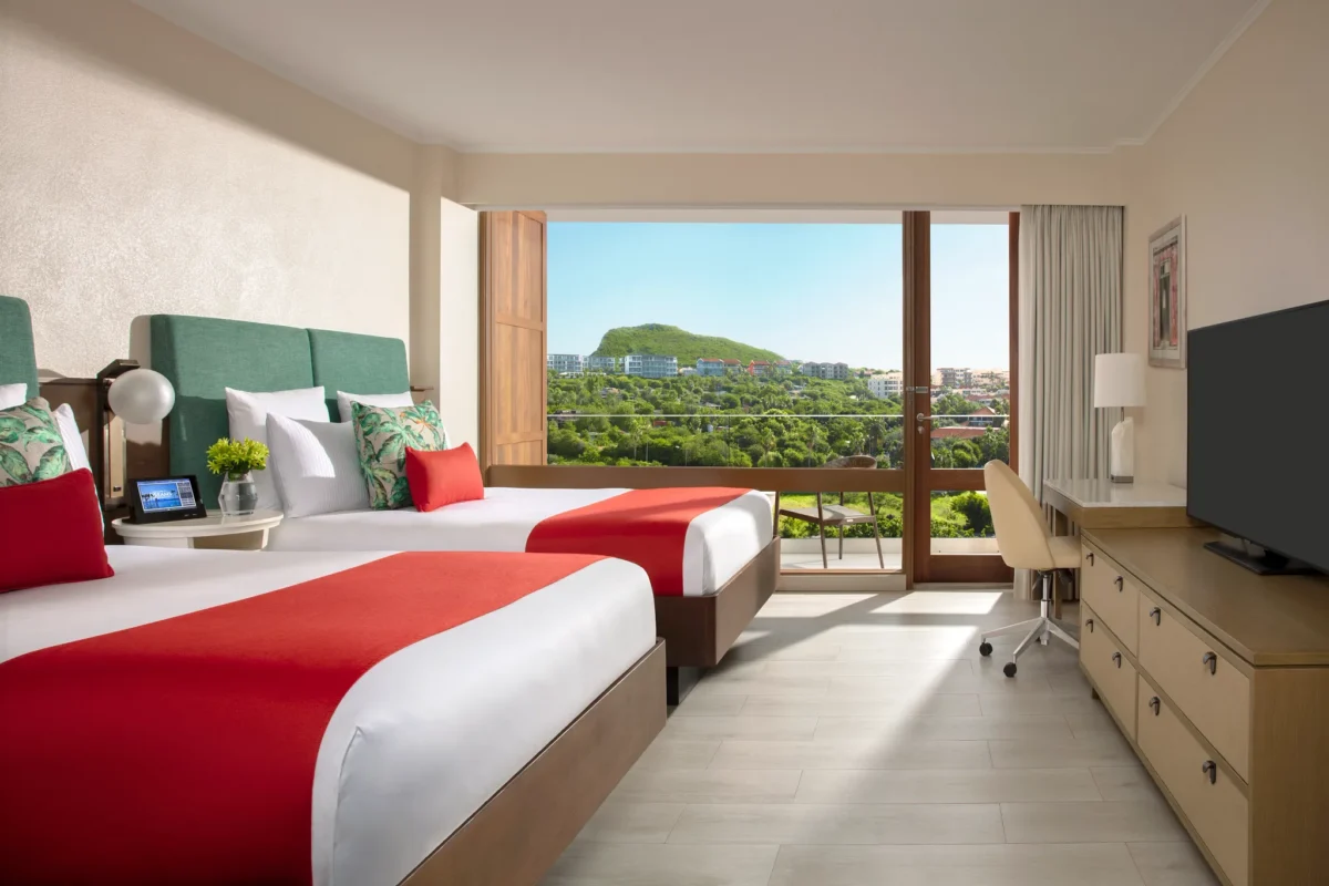 Deluxe Double room with two double beds and furnished balcony overlooking the resort at Dreams Curaçao Resort, Spa & Casino.
