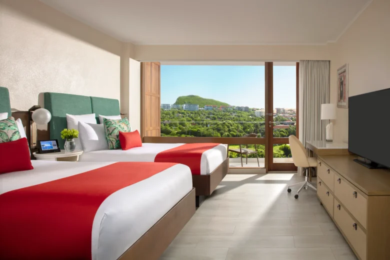 Deluxe Double room with two double beds and furnished balcony overlooking the resort at Dreams Curaçao Resort, Spa & Casino.