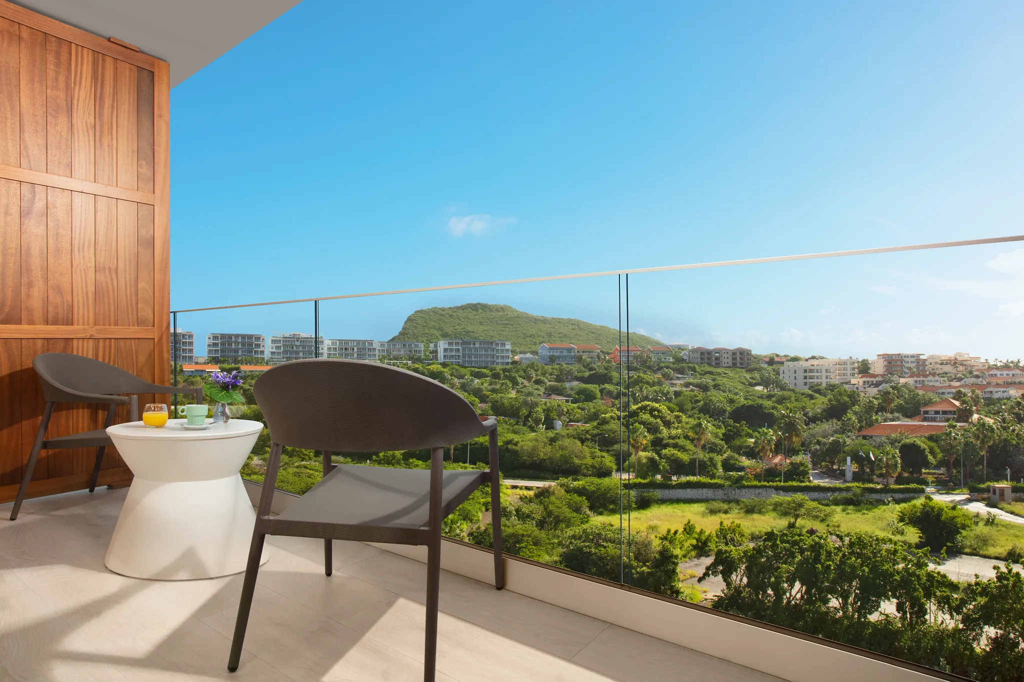 Private furnished balcony with chairs and island view at Deluxe Island View room in Dreams Curaçao Resort.