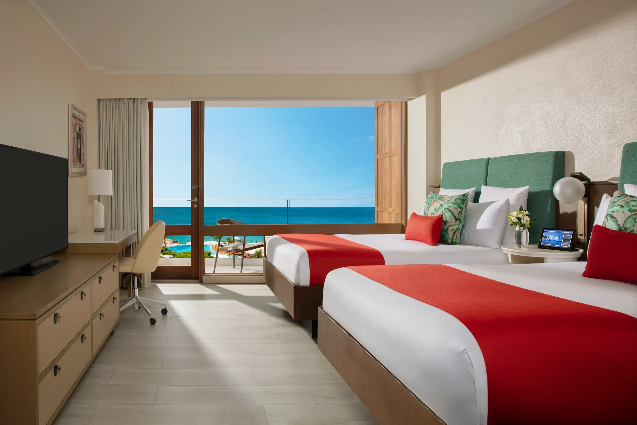 Deluxe Pool View room with two double beds and balcony at Dreams Curaçao Resort overlooking the pool area.