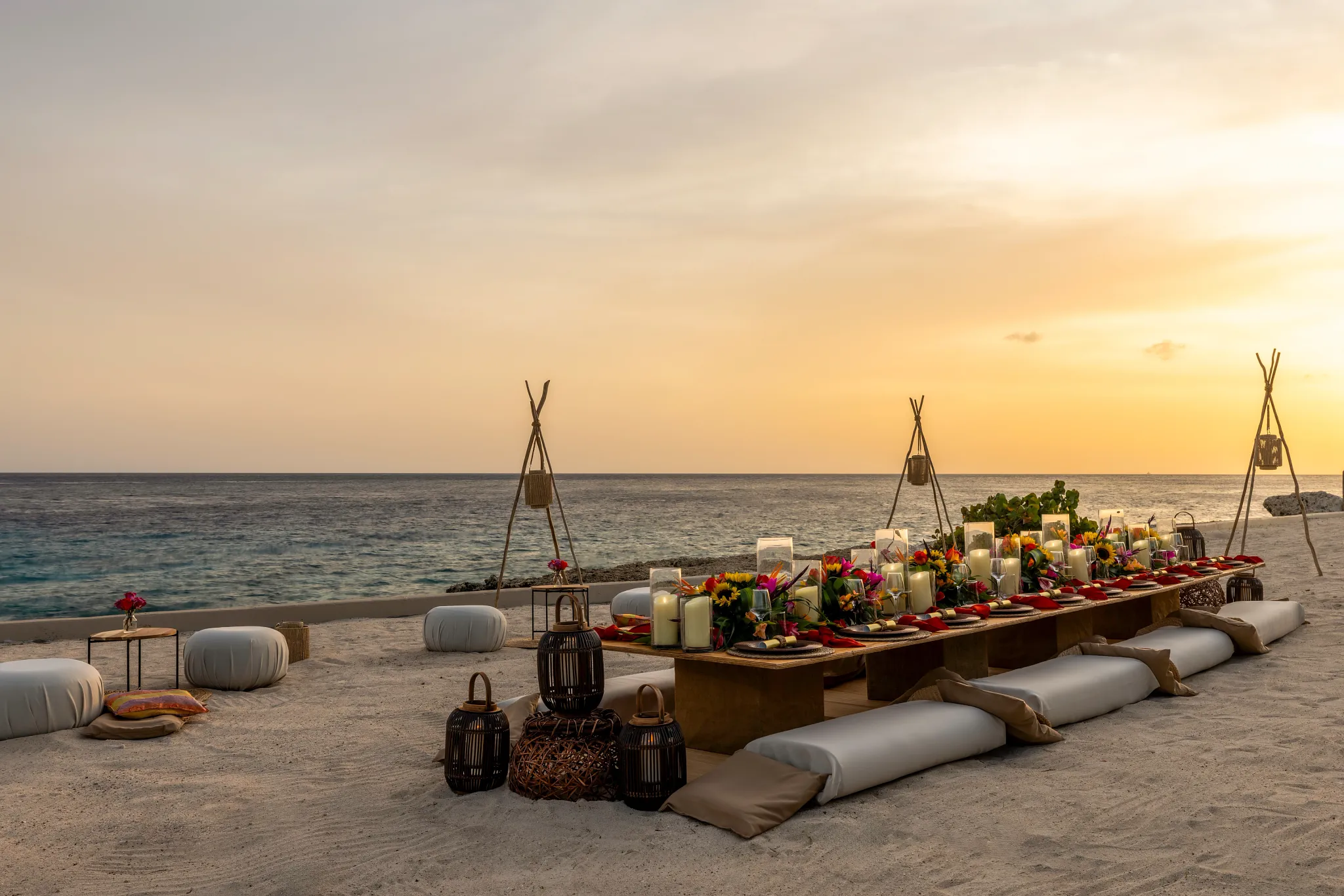 Beachfront dinner setup with candles and decor at sunset at Dreams Curaçao Resort.