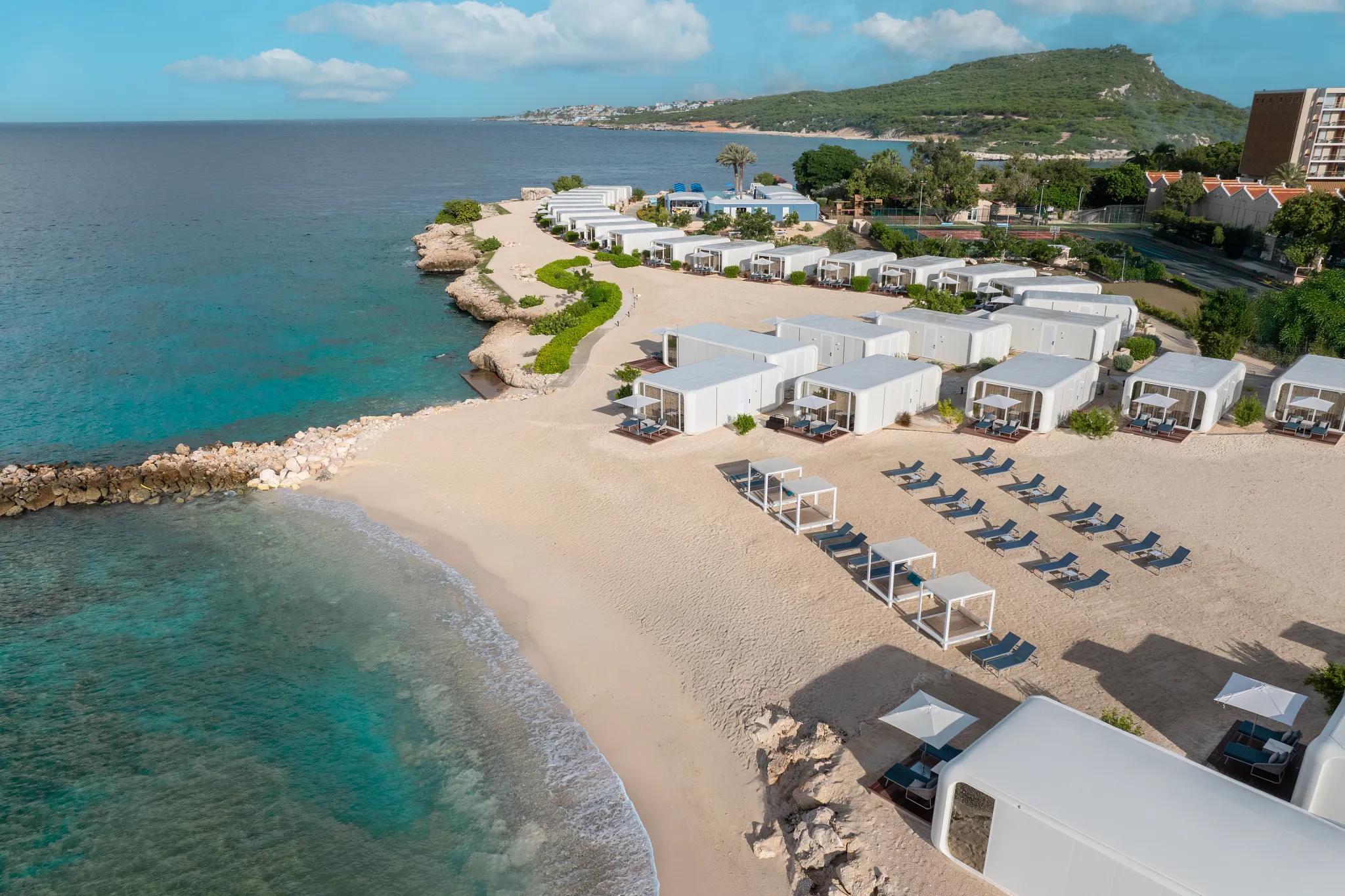 Modern beachfront bungalows lined along the shore at Dreams Curaçao Resort with ocean views.