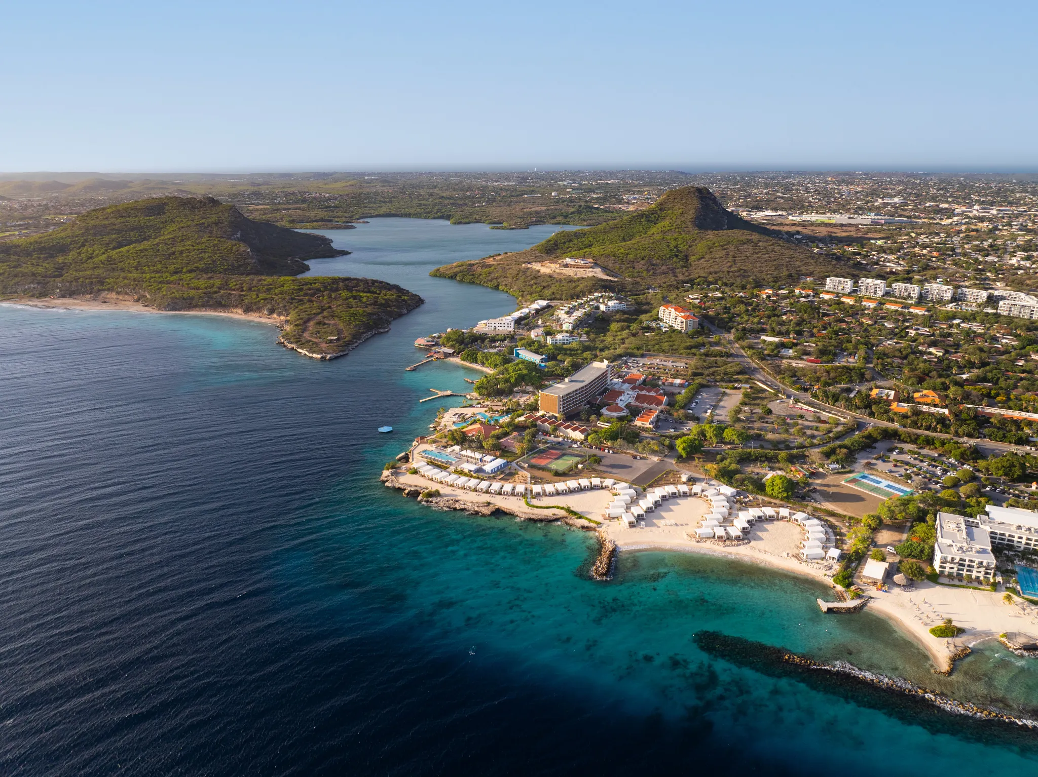 Wide aerial view of Dreams Curaçao Mare beachfront with white cabanas and turquoise shoreline.