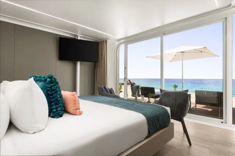 Beachfront bungalow bedroom with sliding glass doors opening to oceanfront terrace at Dreams Curaçao.