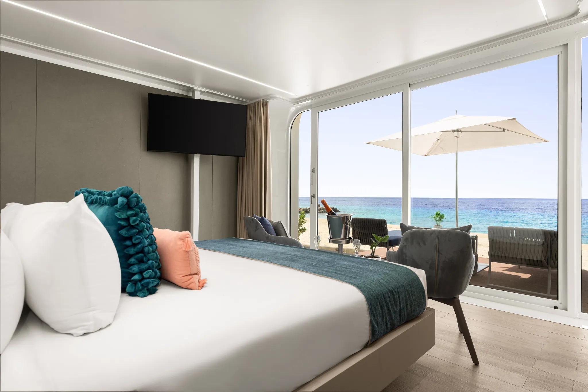 Beachfront bungalow bedroom with sliding glass doors opening to oceanfront terrace at Dreams Curaçao.