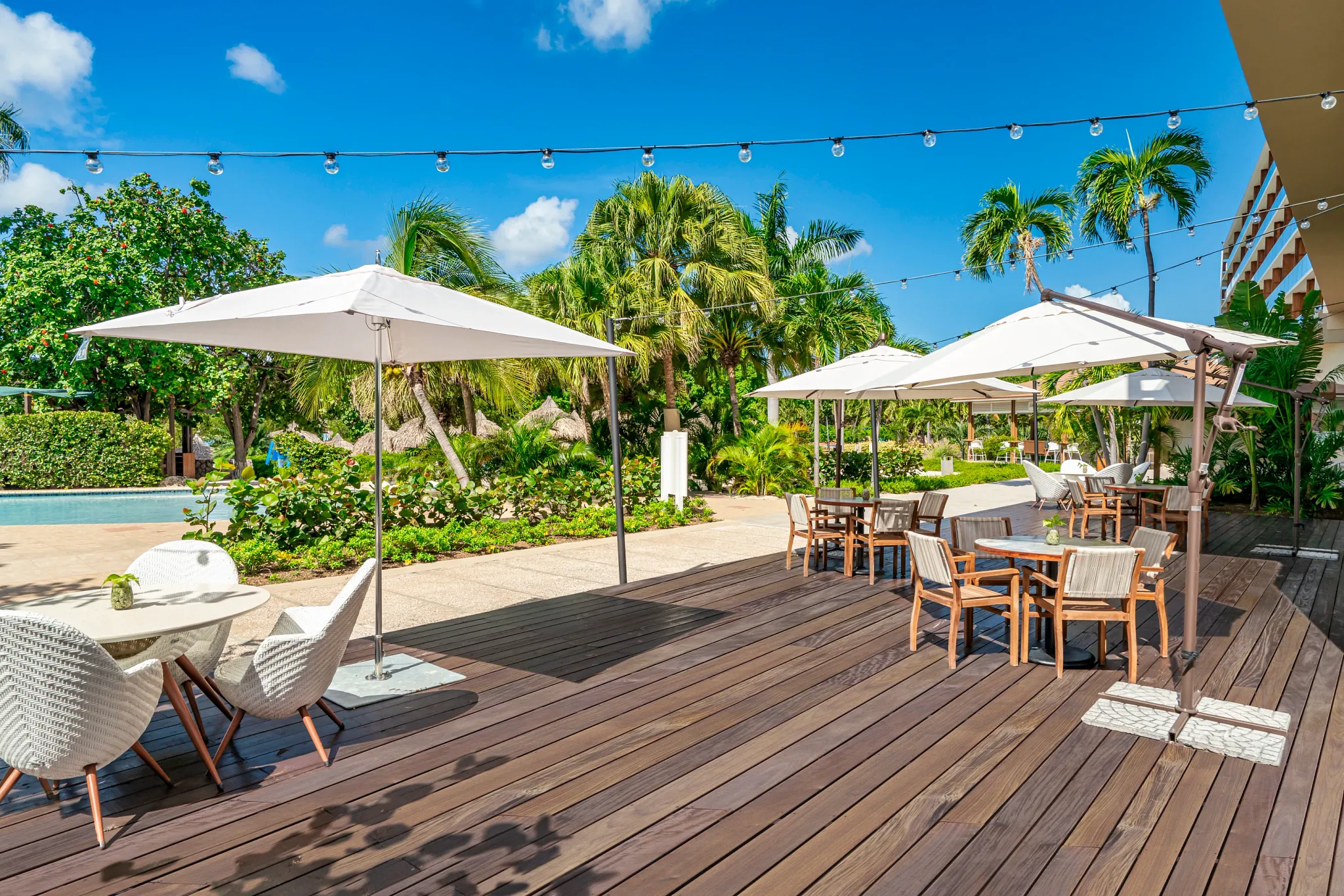 Outdoor terrace dining area with umbrellas and tropical landscaping at Dreams Curaçao Resort.