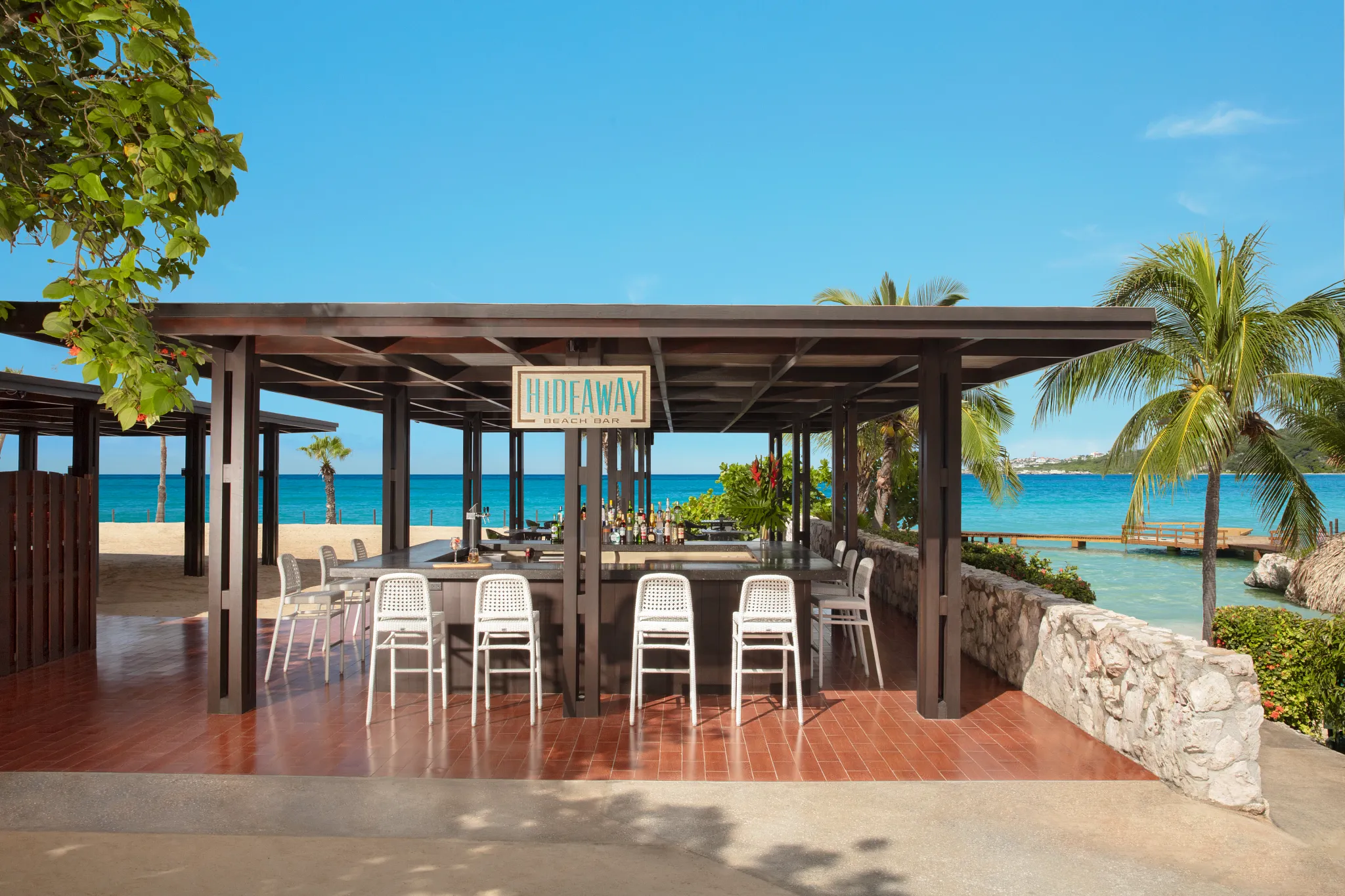 Hideaway beach bar at Dreams Curaçao Resort featuring an open-air seaside bar serving premium cocktails with ocean views.