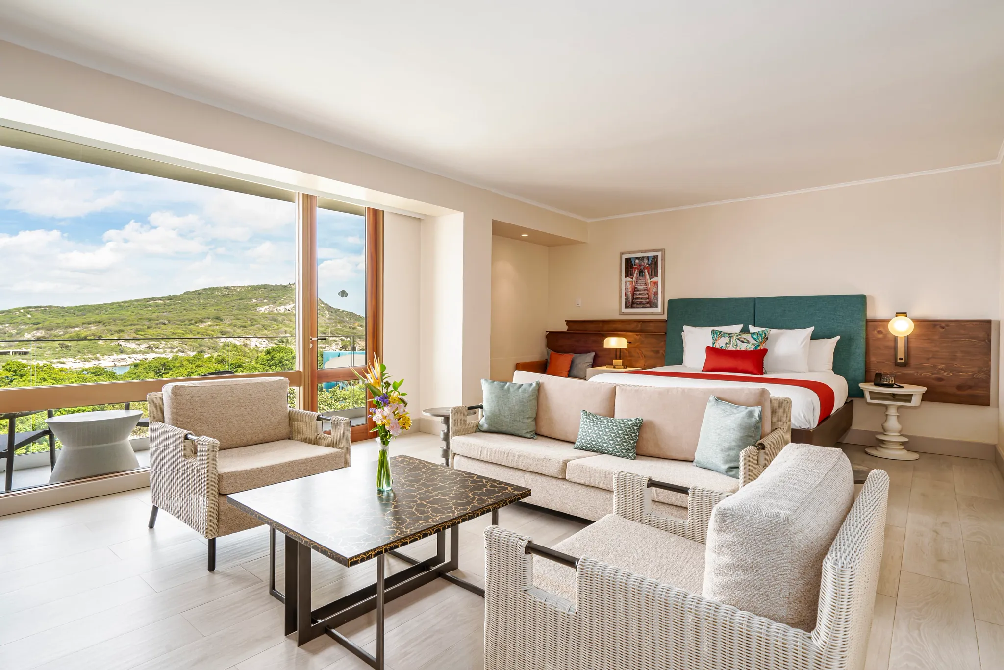 Preferred Club Junior Suite Ocean View with king bed and seating area at Dreams Curaçao Resort overlooking lush island and ocean.