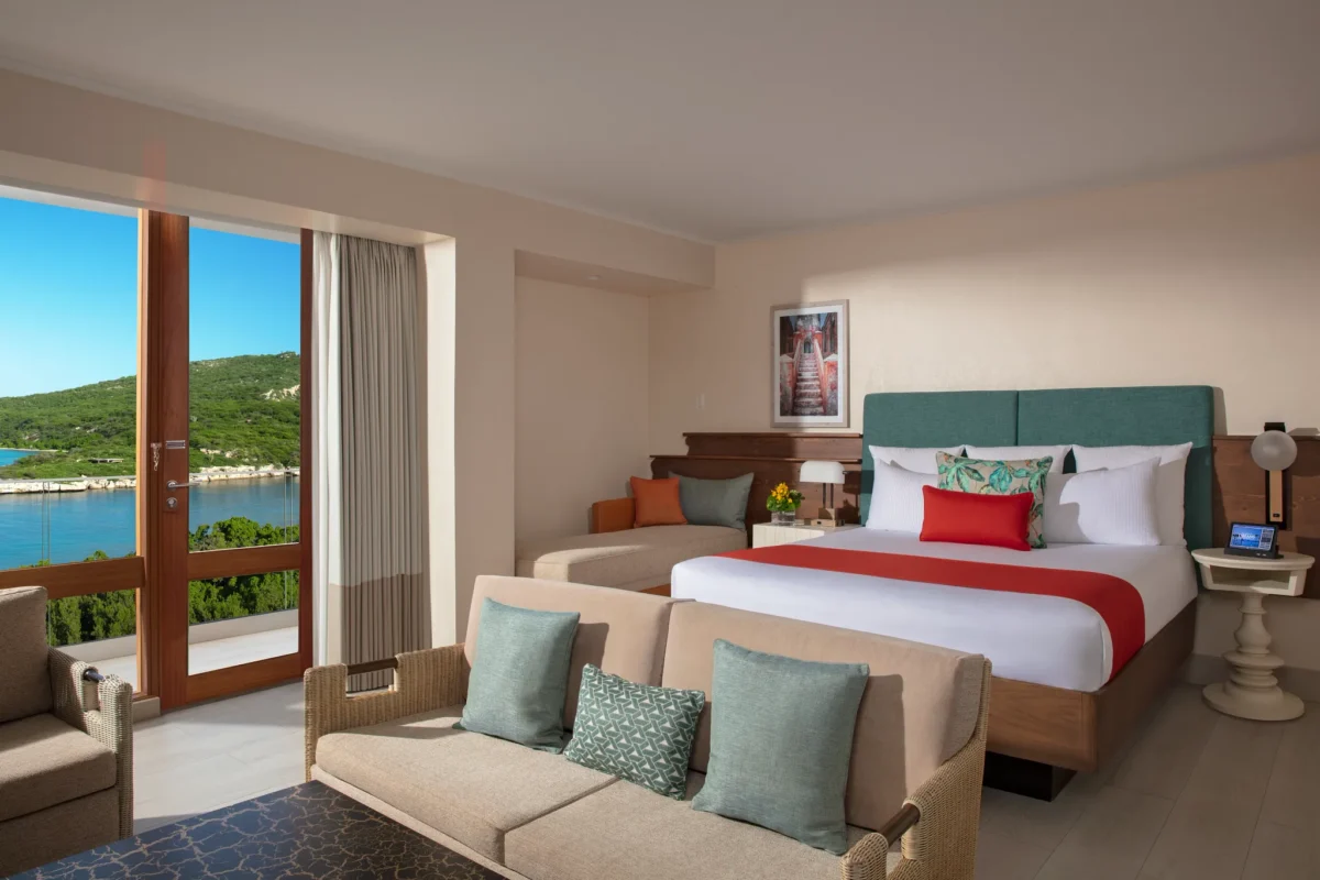 Preferred Club Suite Ocean View with king bed and seating area at Dreams Curaçao Resort overlooking the ocean.