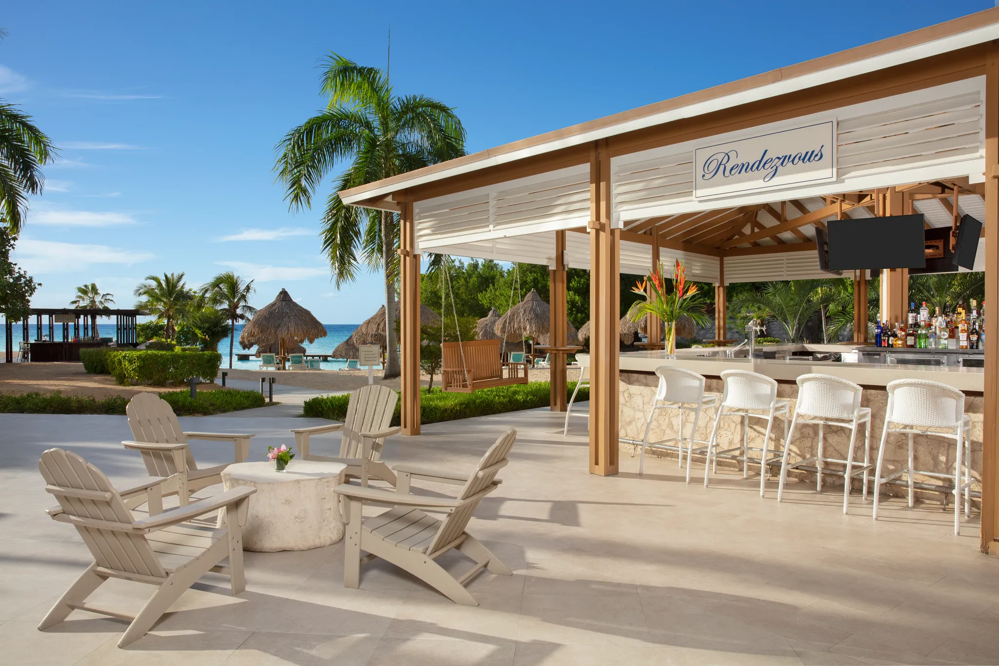 Rendezvous lobby bar at Dreams Curaçao Resort featuring an open-air lounge setting with cocktails and relaxed seating.