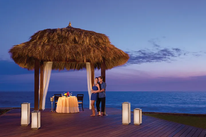 Romantic beachfront palapa dinner setup at sunset at Dreams Curaçao Resort, Spa & Casino